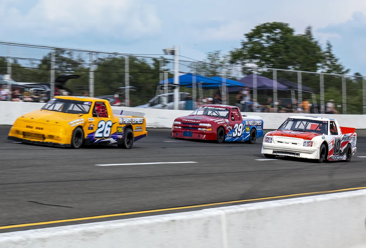 Three race trucks running side by side on the track