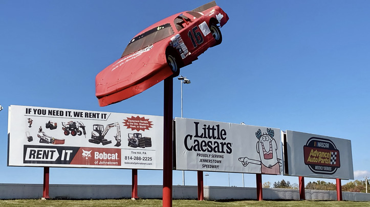 Billboards along the outer wall of turns 1 and 2, beneath the speedway's car-on-a-pole sign