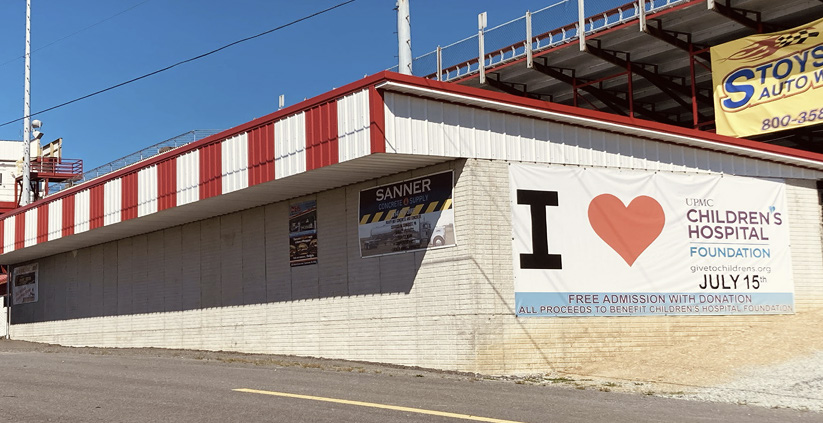 Sponsor banners on the outer walls of the restroom building at the speedway entrance